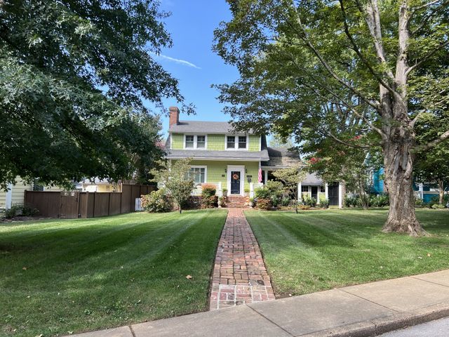a front view of a house with a yard and trees