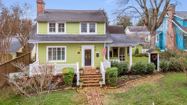 a view of a brick house with a yard and large trees