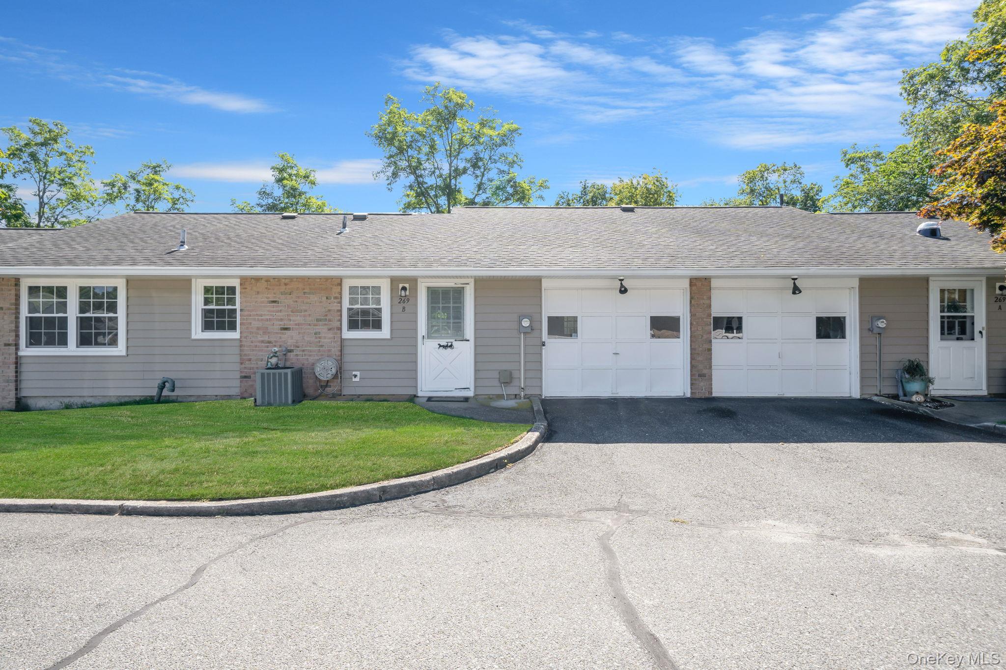 Single story home with a shingled roof, asphalt driveway, a front lawn, and an attached garage