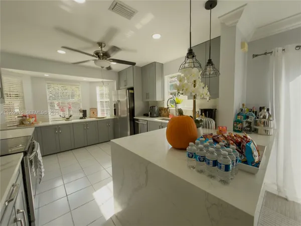 a kitchen with stainless steel appliances kitchen island granite countertop a sink refrigerator stove and microwave