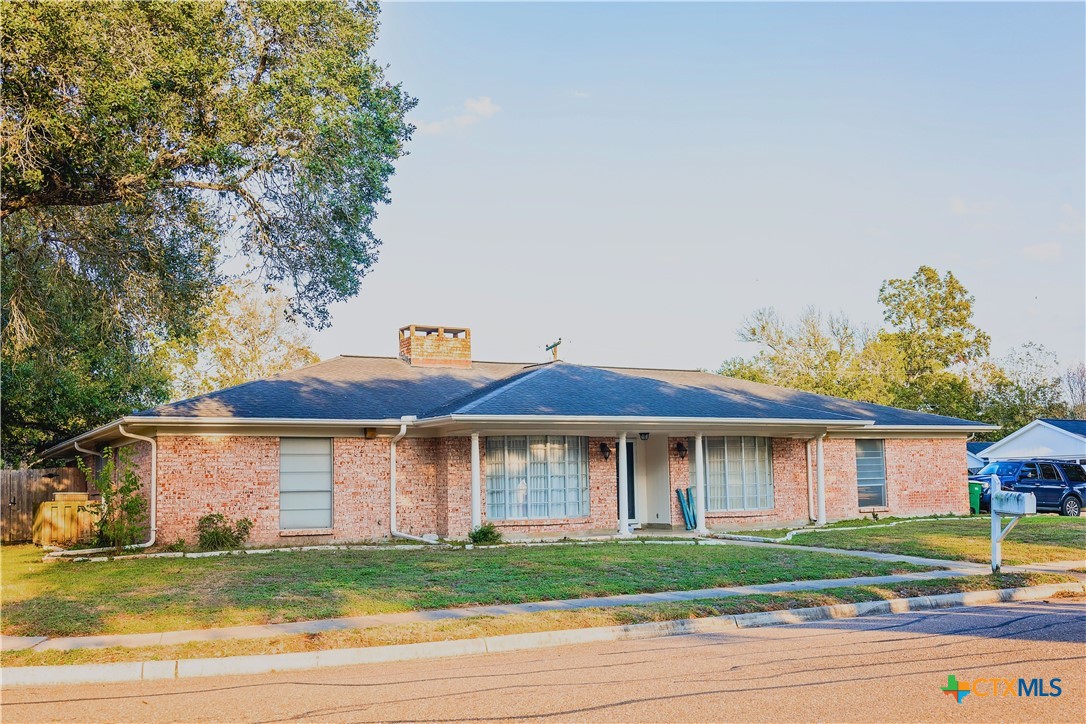 a front view of a house with a garden and a tree