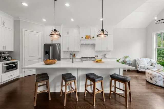 a kitchen with stainless steel appliances granite countertop a refrigerator a sink a stove and a wooden floor