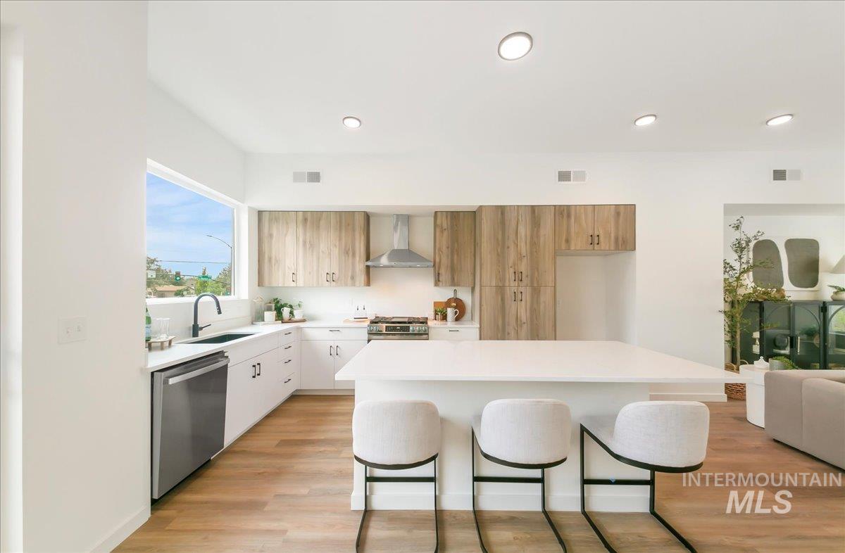 2032 South Mackinnon Lane Boise, ID 83706 - Photo 20 of 48 Kitchen with modern cabinets, a breakfast bar, appliances with stainless steel finishes, wall chimney exhaust hood, and a kitchen island