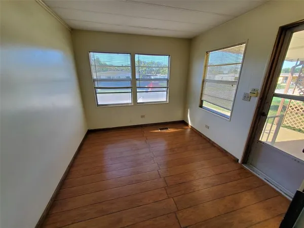 a view of an empty room with a window and wooden floor