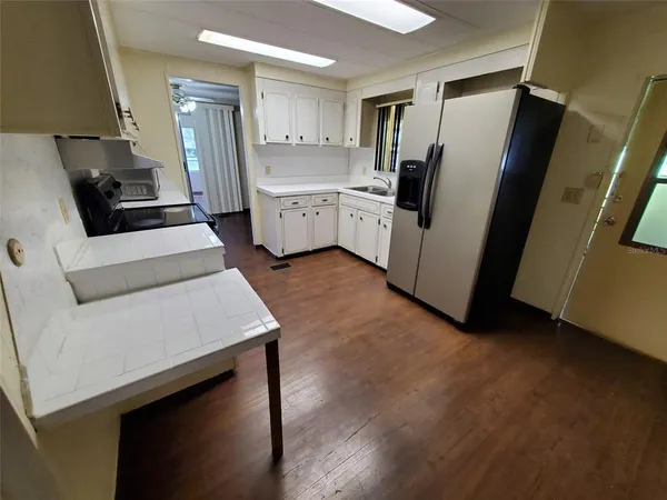 a kitchen with stainless steel appliances a refrigerator a sink a stove and white cabinets