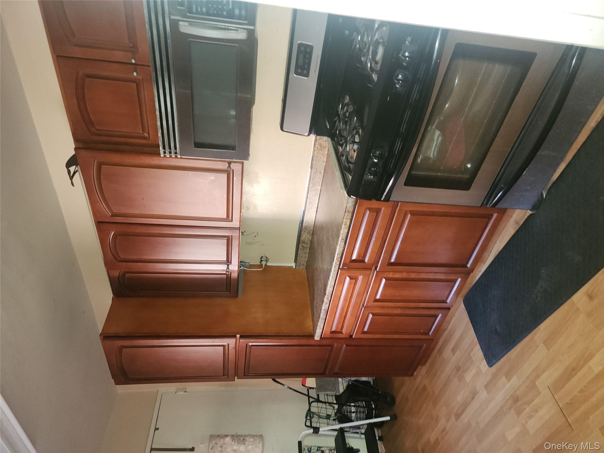 99-11 60th Avenue, Unit 3E Queens, NY 11368 - Photo 9 of 12 a kitchen with wooden cabinets and a stove top oven