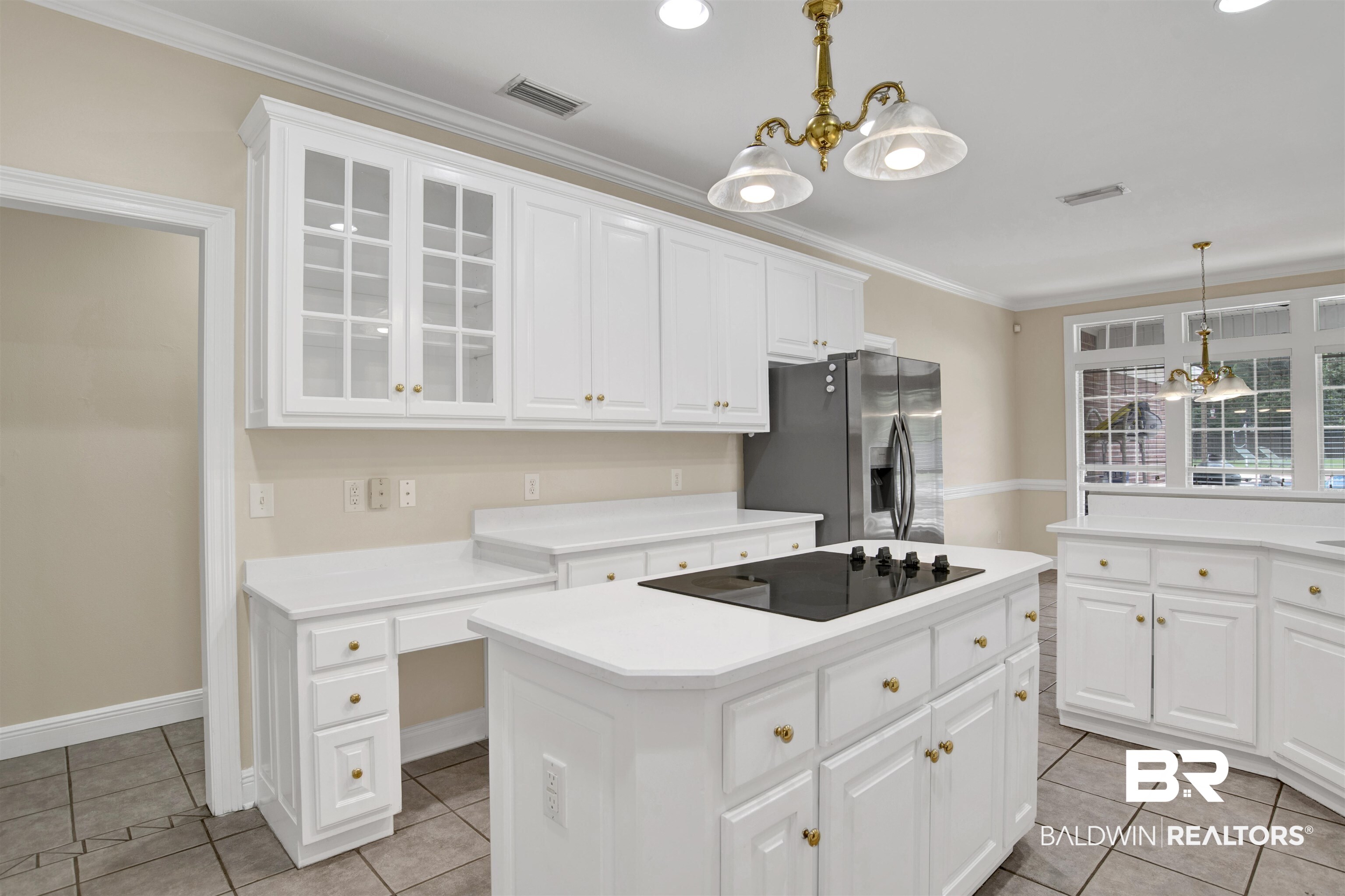 8847 Dawes Lake Road South Mobile, AL 36619 - Photo 11 of 47 Expansive kitchen featuring white cabinetry with brass hardware, a center island with a built-in cooktop, and a stainless steel refrigerator