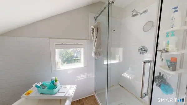 a bathroom with a tub shower and window