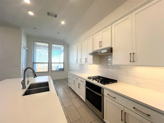 a kitchen with stainless steel appliances a sink a stove and white cabinets