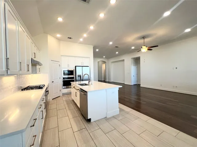a large kitchen with stainless steel appliances kitchen island a large counter top and a stove