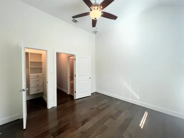 an empty room with wooden floor closet and windows