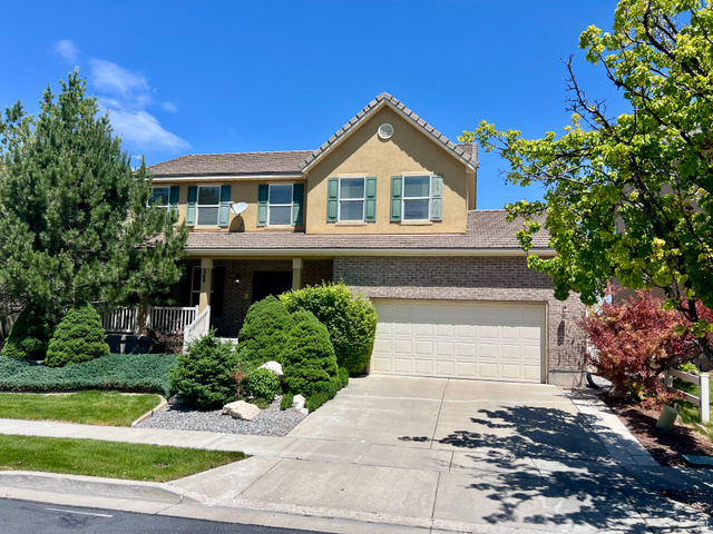 369 Culross Circle Tooele, UT 84074 - Photo 1 of 54 Two-story stucco and brick exterior featuring a covered front porch, an attached two-car garage, mature landscaping, and a concrete driveway