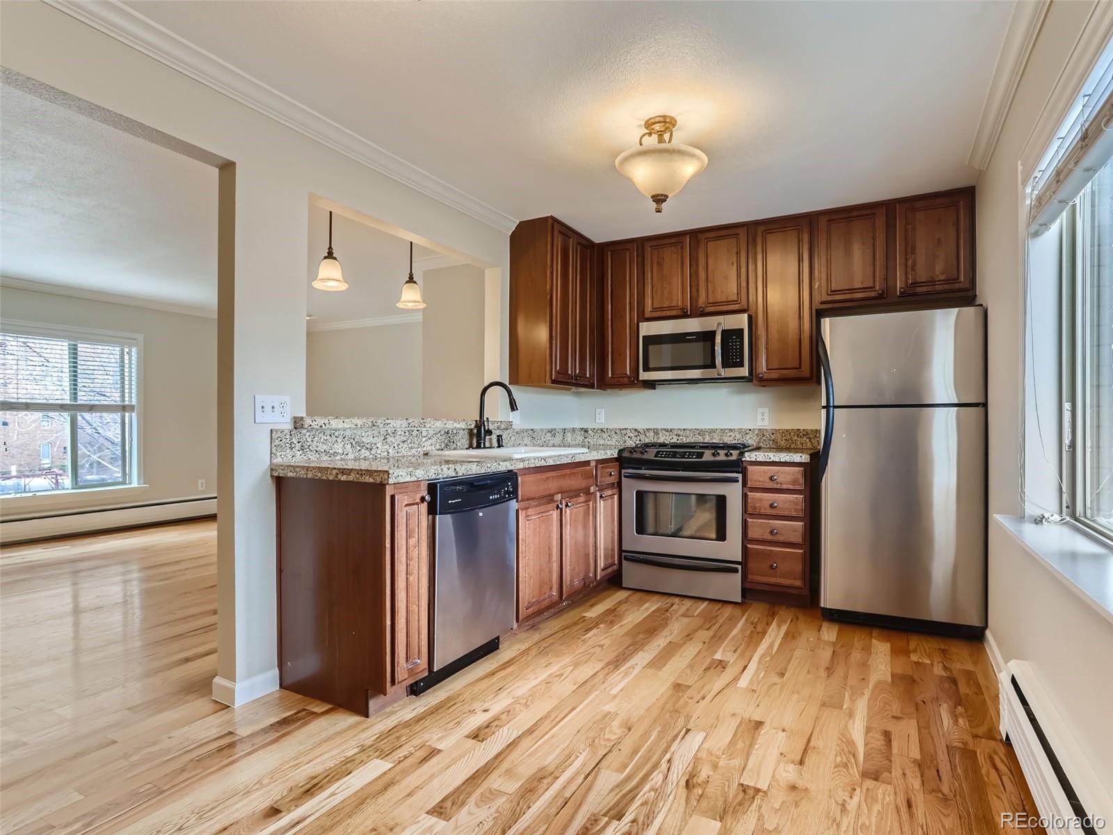 920 Eudora Street, Unit 202 Denver, CO 80220 - Photo 5 of 11 a kitchen with granite countertop wooden floors a stove and a refrigerator