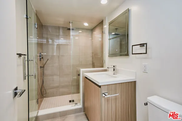 a bathroom with a shower sink vanity and toilet