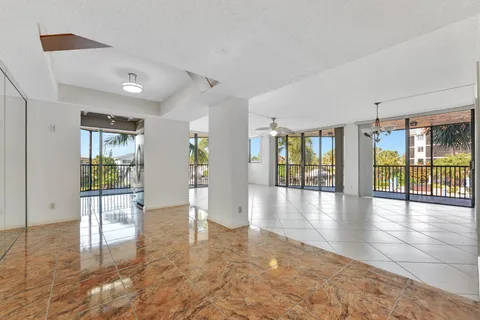an empty room with wooden floor chandelier and windows