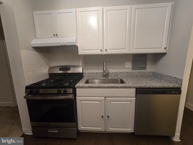 a kitchen with granite countertop white cabinets and a stove