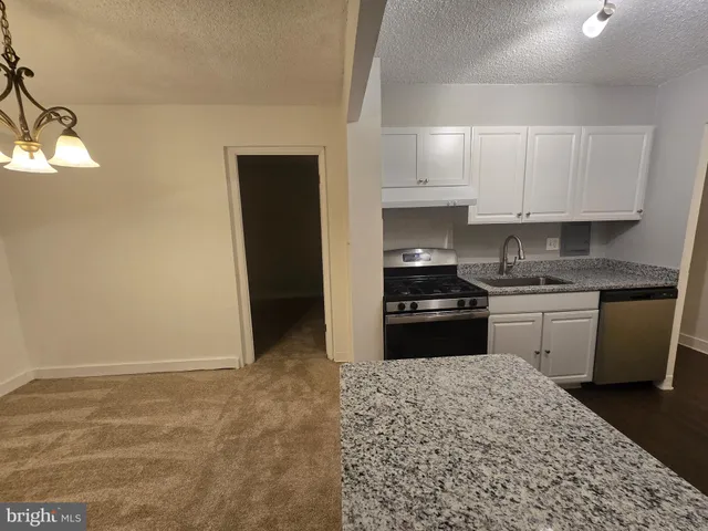 a kitchen with granite countertop white cabinets and refrigerator
