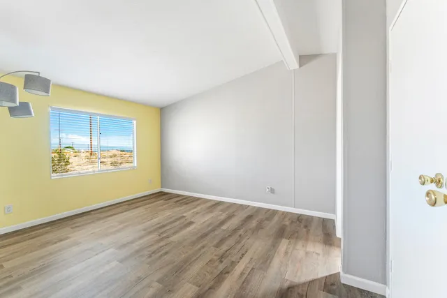 a view of an empty room with wooden floor and closet