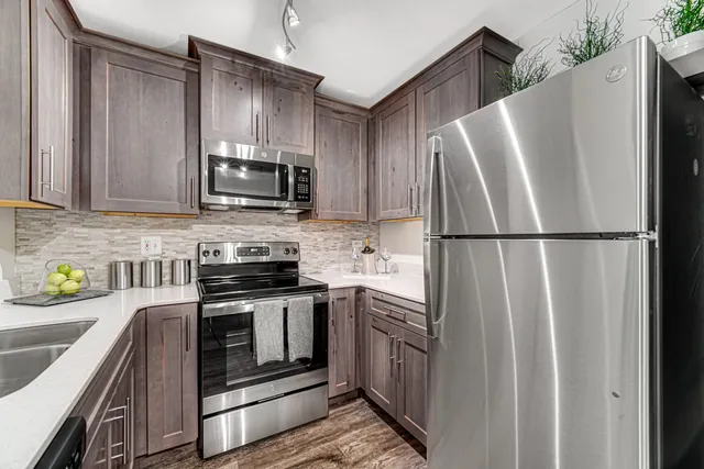 a kitchen with stainless steel appliances granite countertop a refrigerator a stove a sink and a microwave