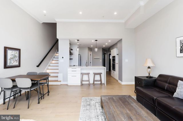 a living room with furniture and a dining table with wooden floor