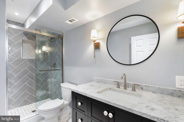 a bathroom with a granite countertop toilet a sink and a mirror