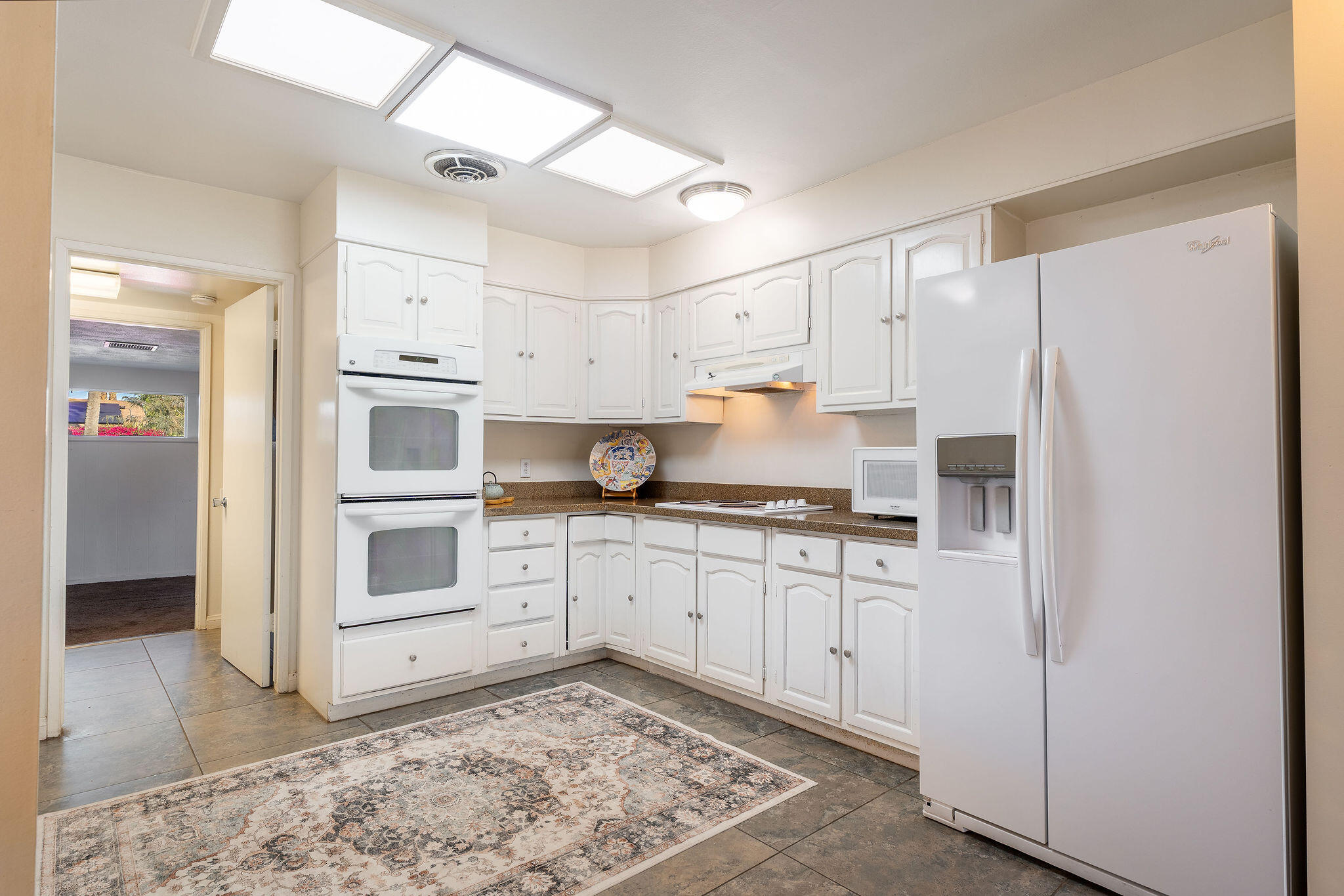 42735 Kansas Street Palm Desert, CA 92211 - Photo 17 of 48 a kitchen with stainless steel appliances granite countertop a refrigerator sink and white cabinets