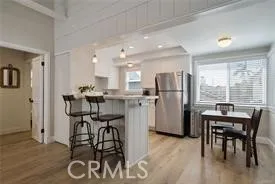 a kitchen with a dining table chairs appliances and wooden floor