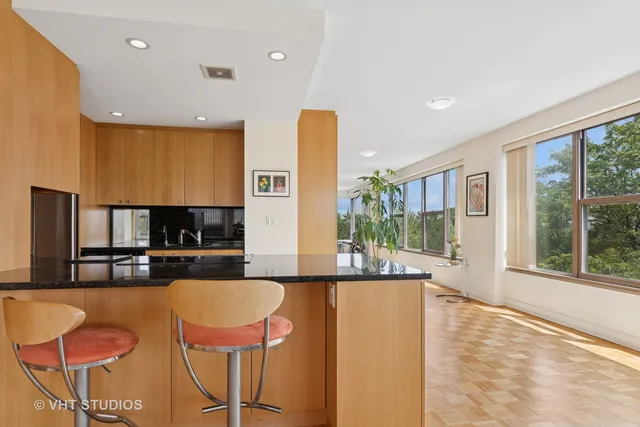 a kitchen with stainless steel appliances granite countertop a stove top oven a sink and a dining table with granite countertops