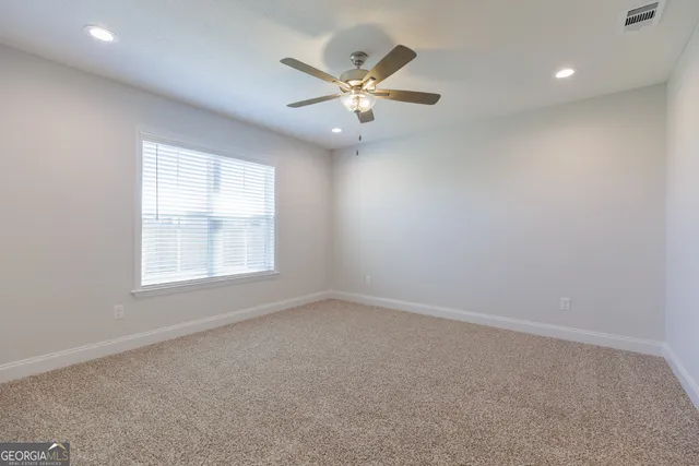 an empty room with a window and a ceiling fan