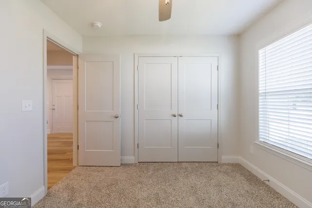 an empty room with windows and fan