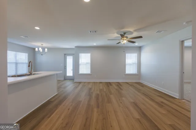 a view of an empty room with a window and wooden floor