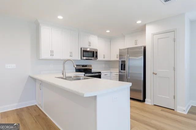 a kitchen with a refrigerator a sink a stove a microwave and wooden floor