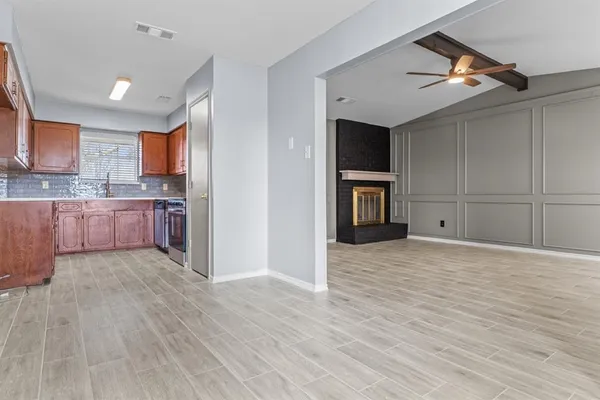 a view of kitchen and empty room with wooden floor and cabinet