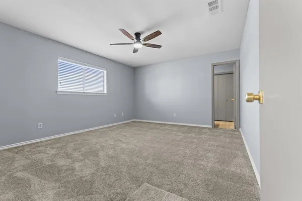 an empty room with windows and fan