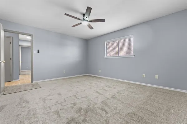 an empty room with a ceiling fan and window