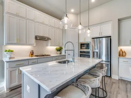 a kitchen with granite countertop a table chairs stainless steel appliances and wooden floor