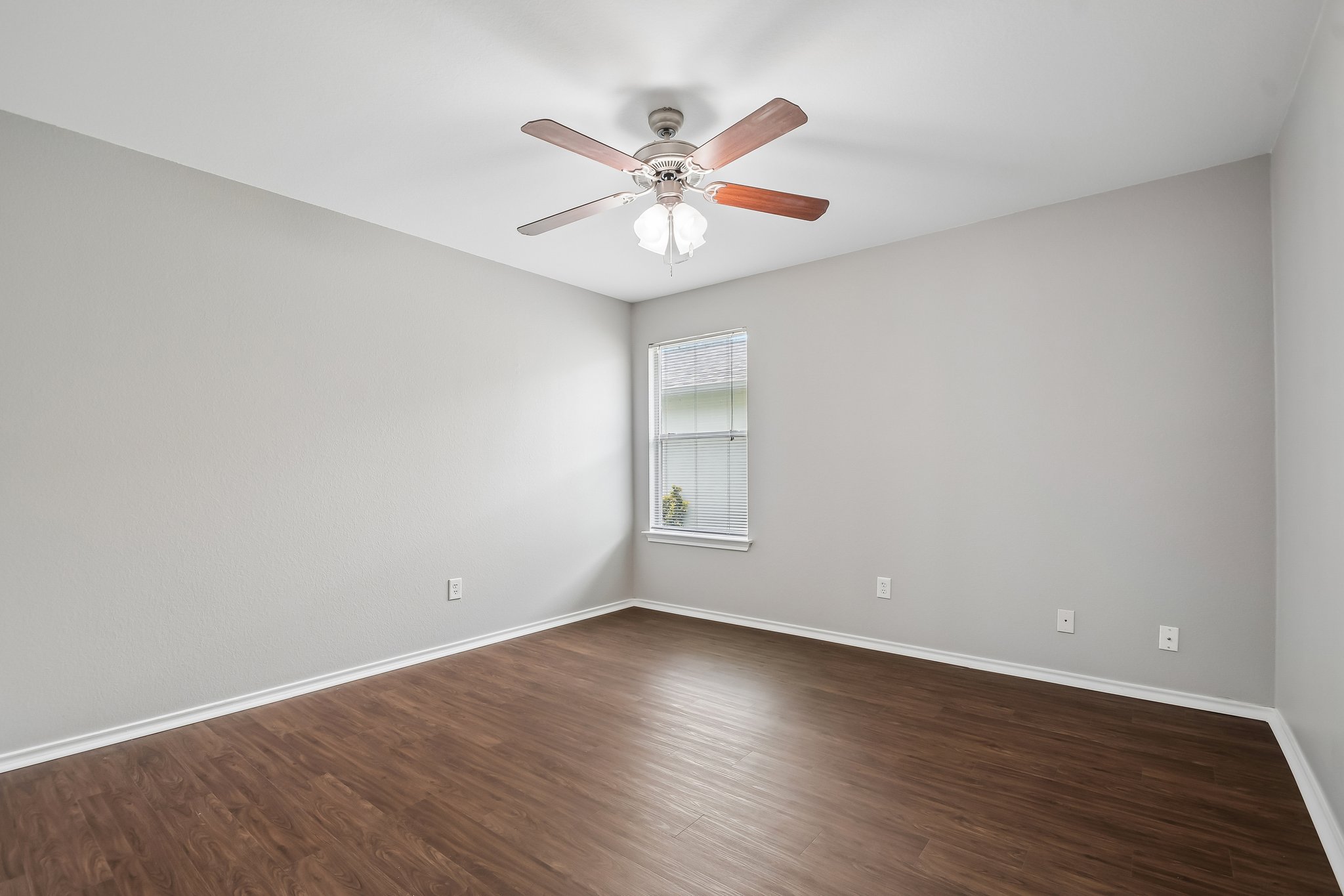 610 Lavaca Loop Elgin, TX 78621 - Photo 25 of 37 A well-lit bedroom showcasing rich wood-tone flooring and a classic ceiling fan.