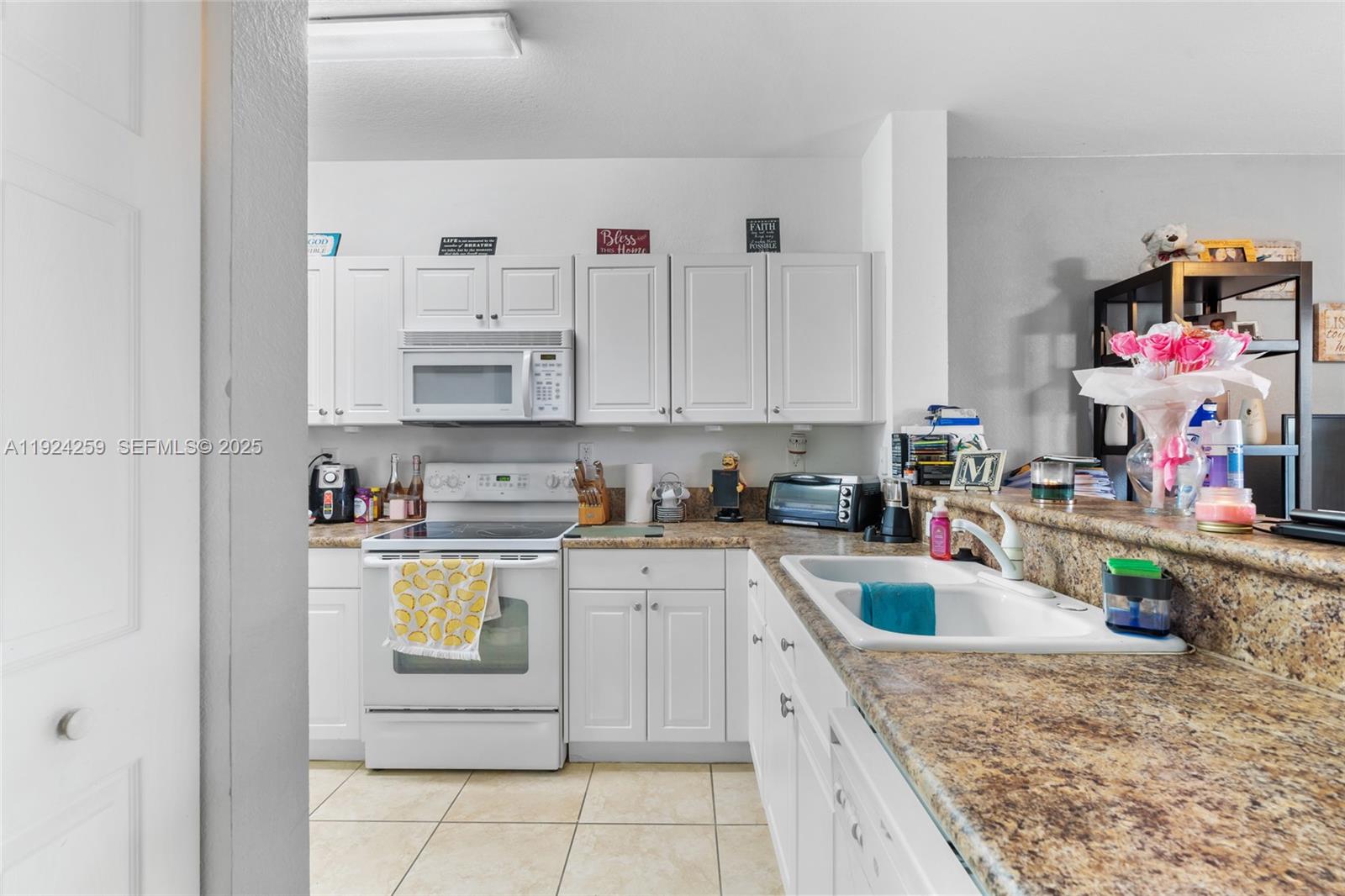 230 Southeast 29th Avenue, Unit 12 Homestead, FL 33033 - Photo 8 of 29 a kitchen with kitchen island granite countertop lots of white stainless steel appliances granite countertop a sink dishwasher and cabinets with wooden floor