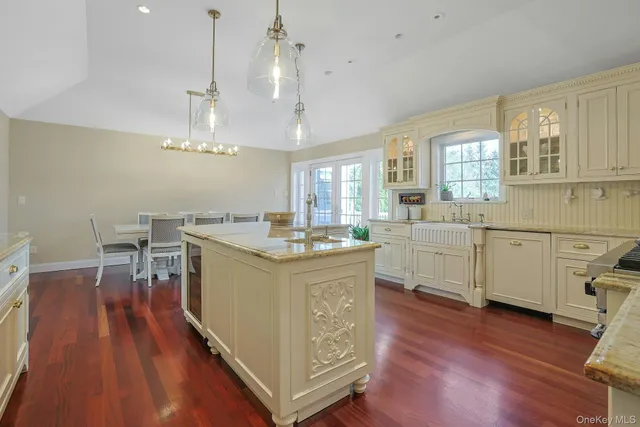 a large kitchen with cabinets a sink dishwasher a stove and a dining table with wooden floor