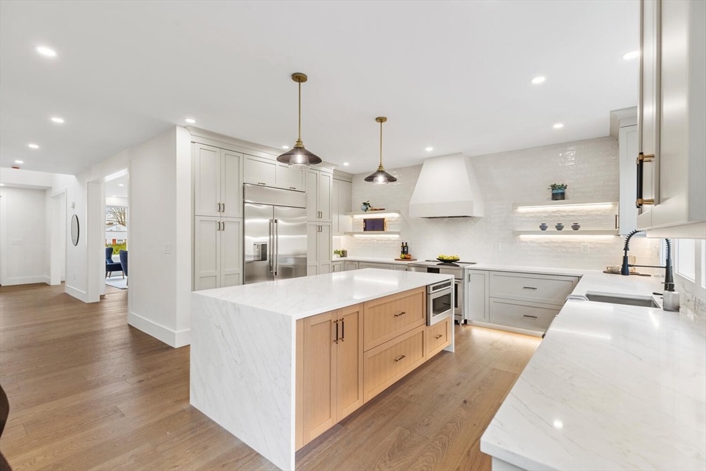 16 Estabrook Road Lexington, MA 02421 - Photo 10 of 38 a large kitchen with stainless steel appliances kitchen island a large counter top a stove a sink dishwasher and a view of living room