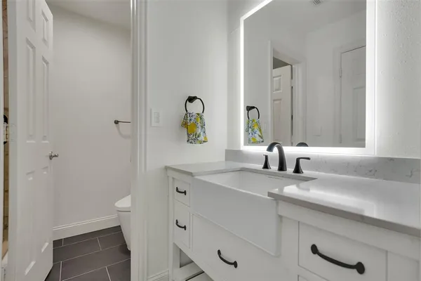a bathroom with a granite countertop sink and a toilet