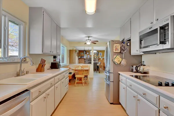 a large white kitchen with lots of counter space sink and appliances