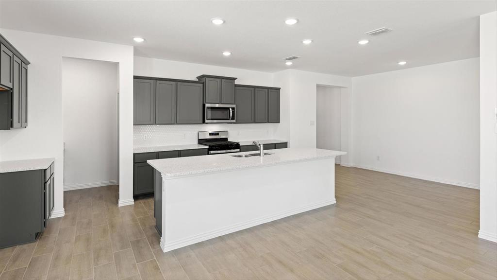 2747 Teton Street Corinth, TX 76210 - Photo 10 of 22 a kitchen with kitchen island a sink a stove and a refrigerator