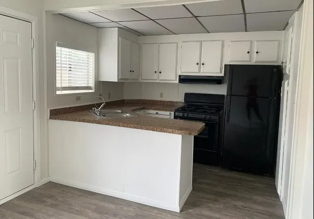 a kitchen with granite countertop white cabinets and refrigerator