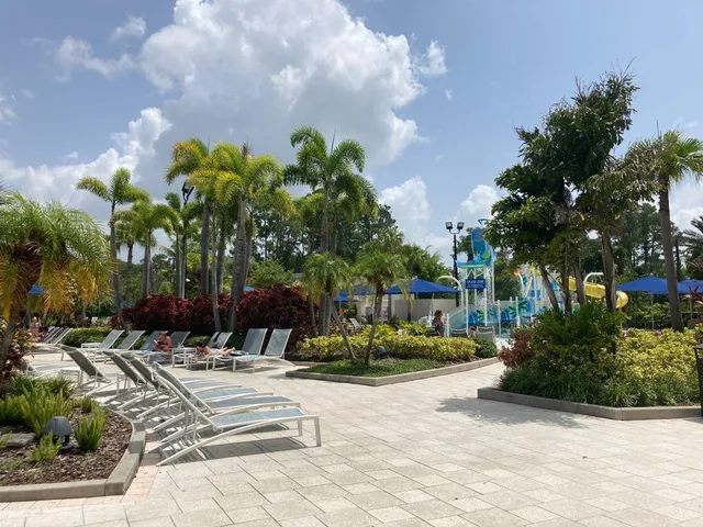 a view of swimming pool with outdoor seating and trees in the background