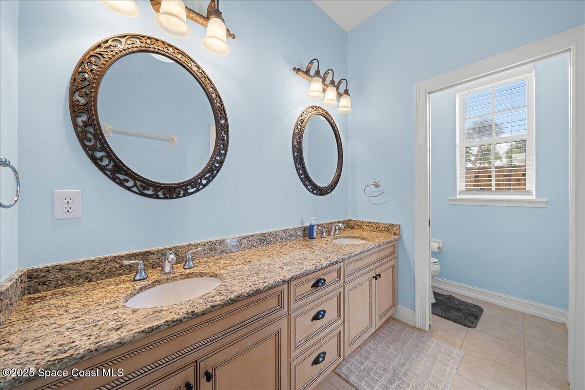 7831 Winona Road Melbourne Beach, FL 32951 - Photo 8 of 41 a bathroom with a granite countertop double vanity sink a mirror and a toilet