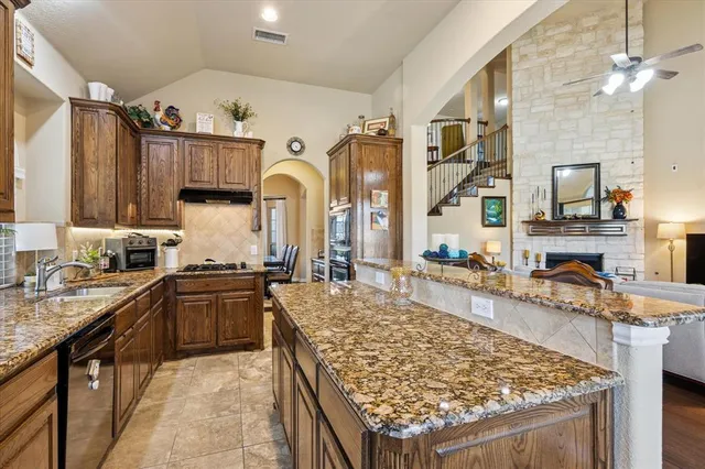 a kitchen with stainless steel appliances granite countertop a sink a stove and a wooden floors