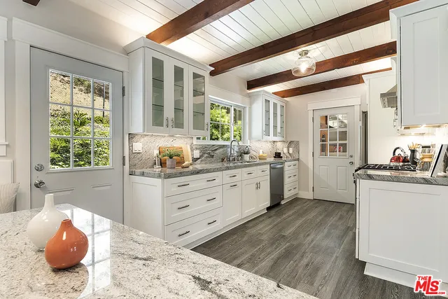 a kitchen with stainless steel appliances kitchen island granite countertop a stove a sink and a granite counter tops with white cabinets