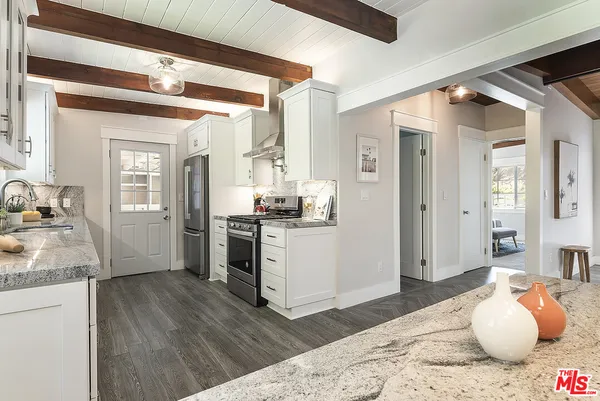 a kitchen view with granite countertop wooden floor and a refrigerator