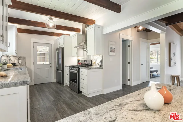 a kitchen view with granite countertop wooden floor and a refrigerator